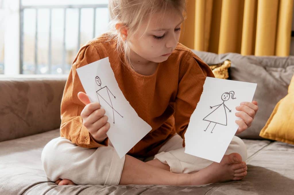 Petite fille tenant un papier déchiré représentant la famille.