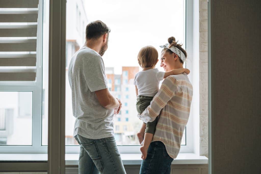 Couple regardant par la fenêtre avant un enfant entre eux.