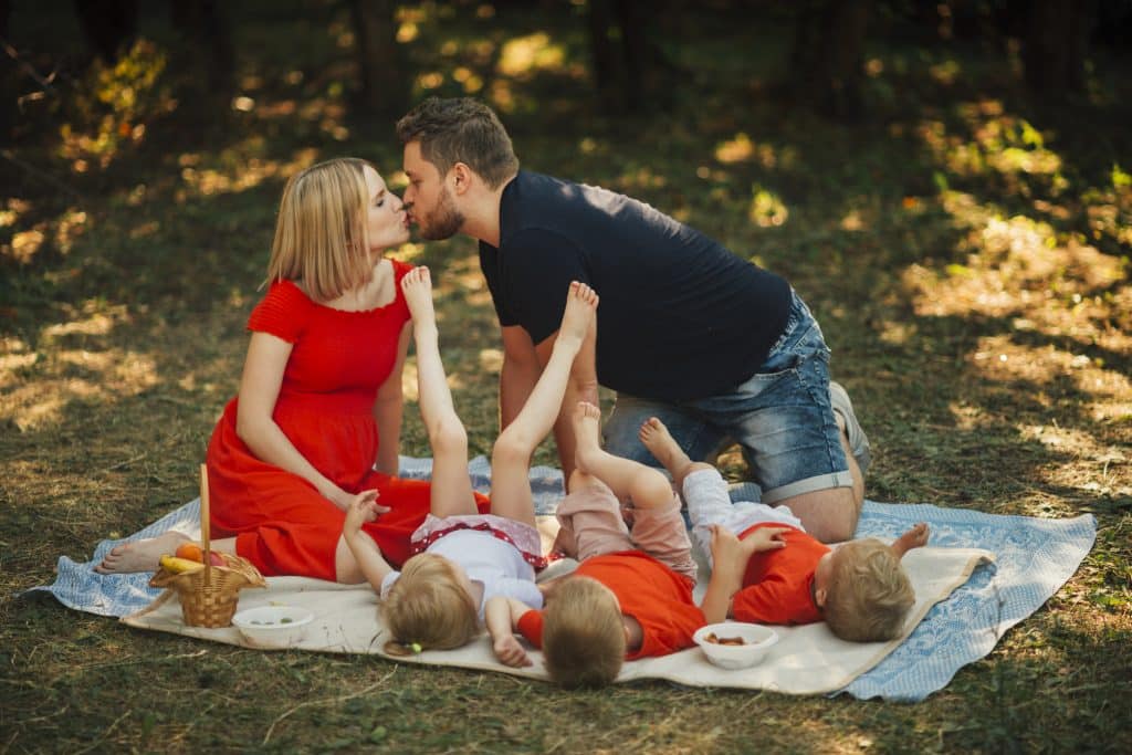Famille nombreuse à un piquenique, les parents s'mbrassent.