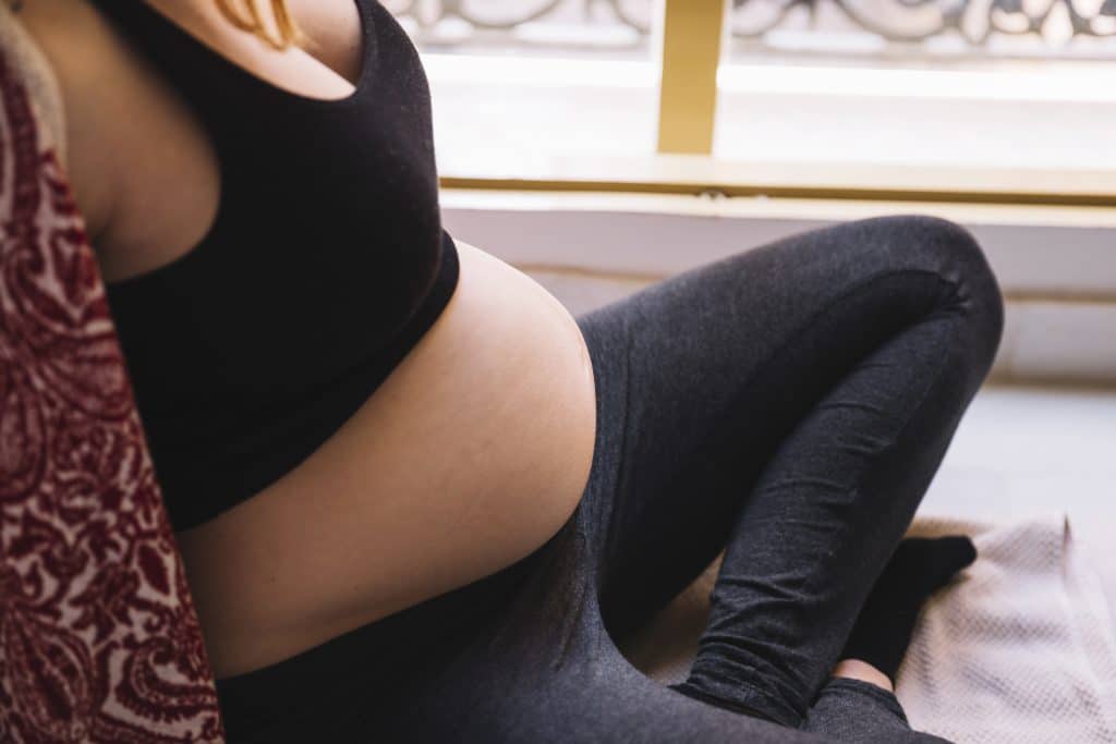 Femme enceinte assise sur un rebord de fenêtre.