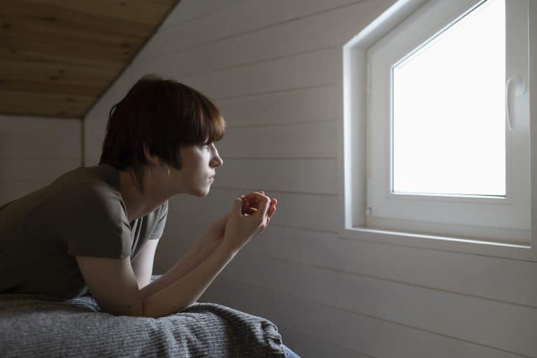 Ado couchée sur son lit regardant pensivement par la fenêtre.