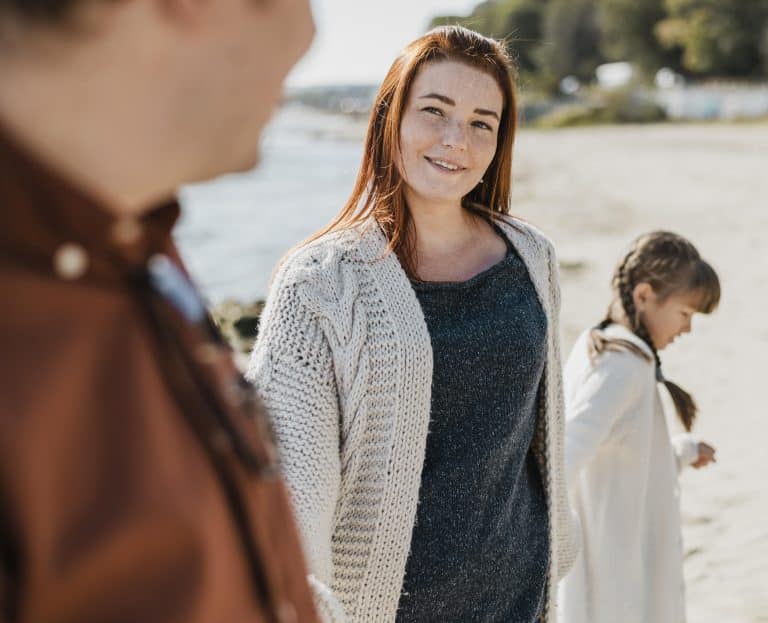 Femme présentant son compagnon à sa fille lors d'une promenade à la plage.